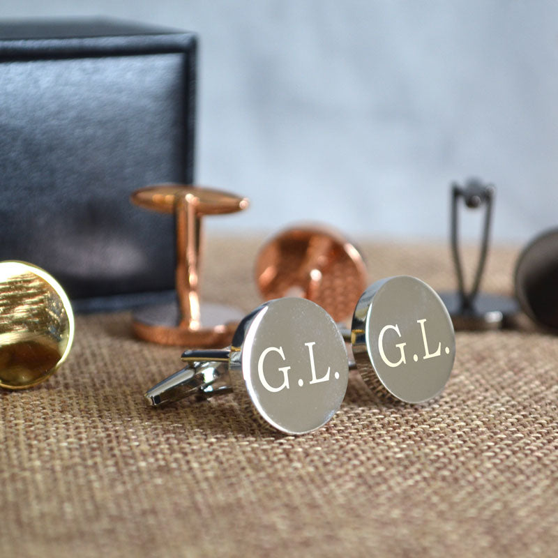 A close up of the round silver cufflinks showing the engraved initials