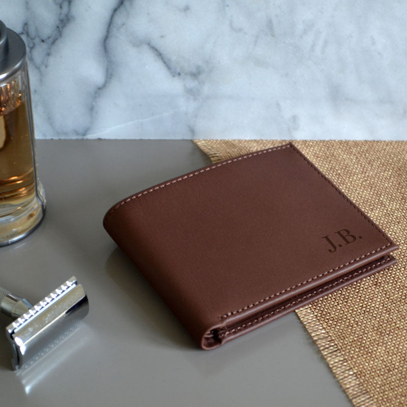 A brown leather wallet made from real leather with the initials J.B. engraved on the front.